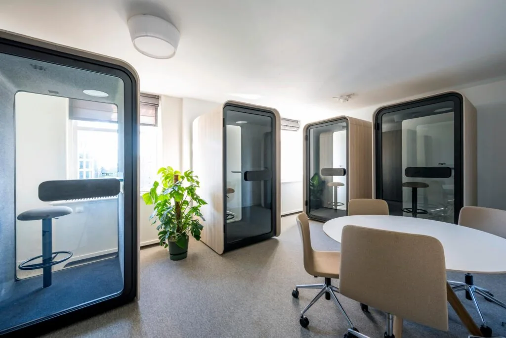 Moderne kantoorruimte aan de Prof. Tulpstraat met vergadertafel, bureaustoelen en drie stille werkpods.